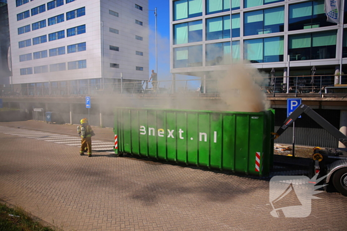 Vlammen slaan uit grote afvalcontainer