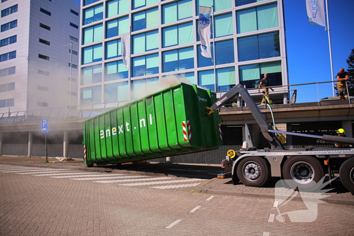 Vlammen slaan uit grote afvalcontainer