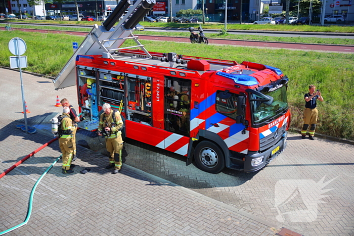 Vlammen slaan uit grote afvalcontainer