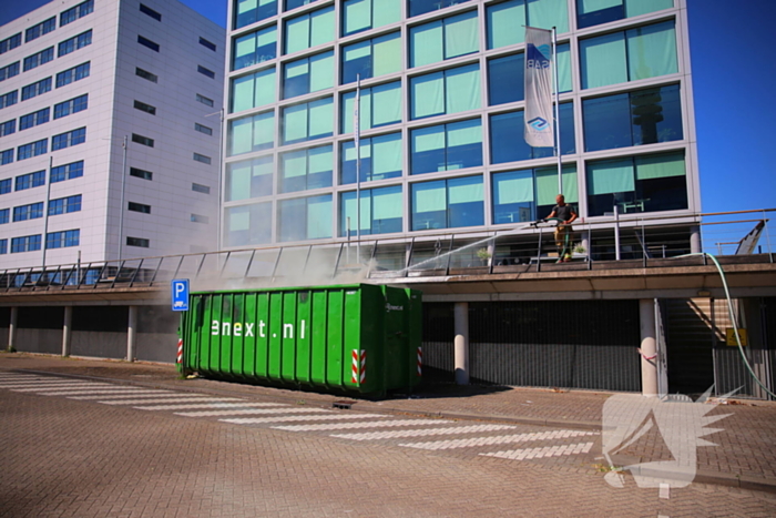 Vlammen slaan uit grote afvalcontainer