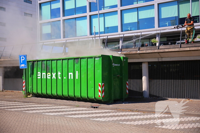 Vlammen slaan uit grote afvalcontainer