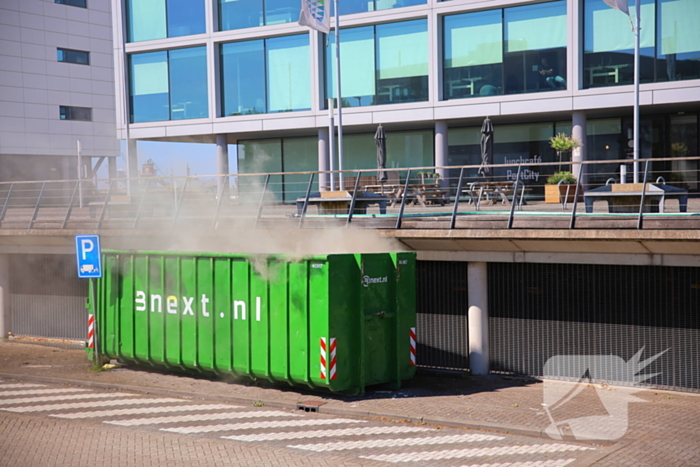 Vlammen slaan uit grote afvalcontainer