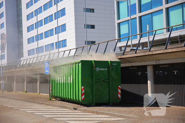 Vlammen slaan uit grote afvalcontainer