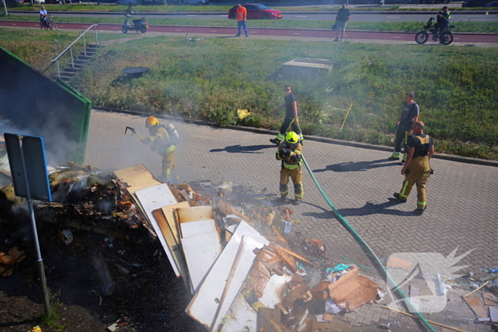 Vlammen slaan uit grote afvalcontainer