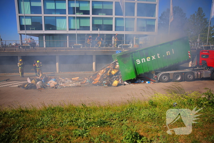 Vlammen slaan uit grote afvalcontainer