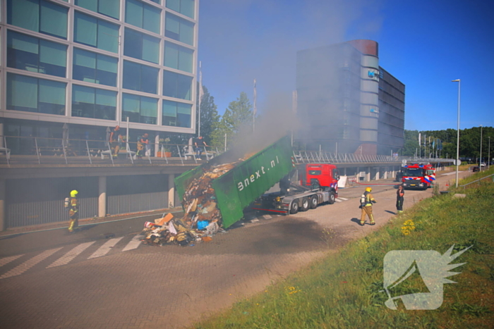 Vlammen slaan uit grote afvalcontainer