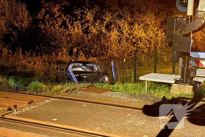 Auto vliegt uit de bocht en knalt tegen hek bij spoorwegovergang