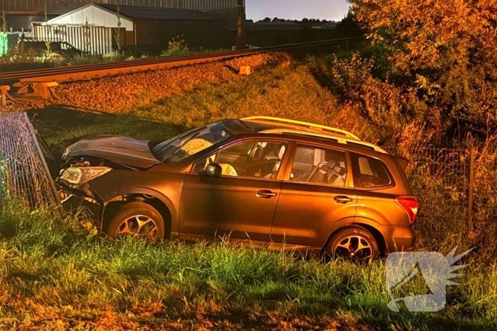 Auto vliegt uit de bocht en knalt tegen hek bij spoorwegovergang