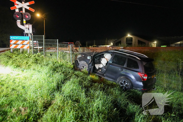 Auto vliegt uit de bocht en knalt tegen hek bij spoorwegovergang
