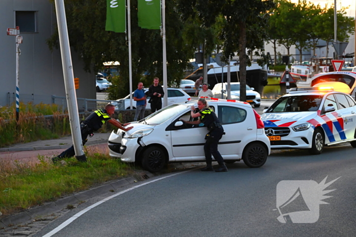 Auto crasht op rotonde en raakt paal