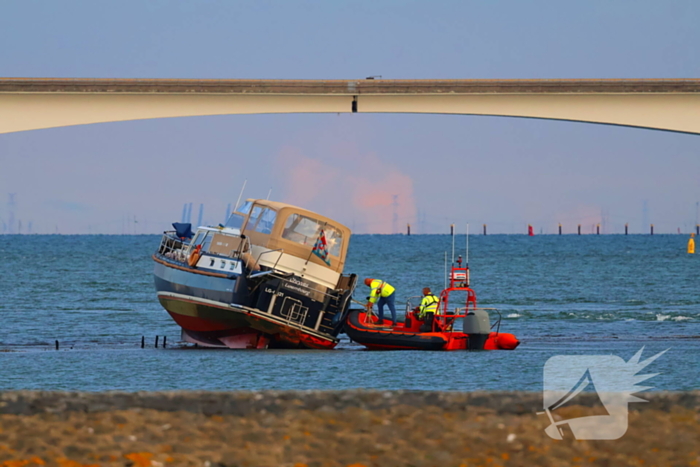 Boot loopt vast op dam, bergingsbedrijf schiet te hulp