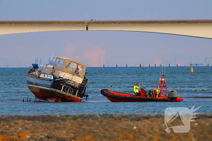 Boot loopt vast op dam, bergingsbedrijf schiet te hulp