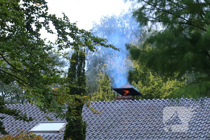 Vlammen slaan uit schoorsteen