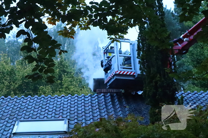 Vlammen slaan uit schoorsteen