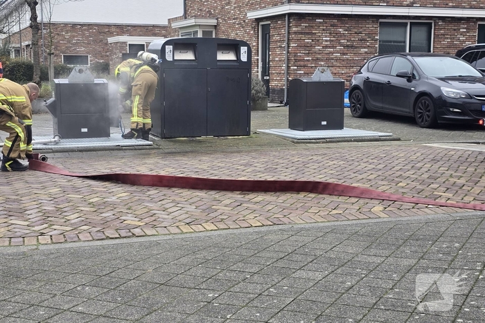 Container vat vlam door vuurwerk, omstanders doen bluspoging
