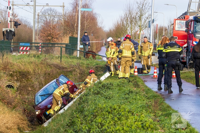 Auto op zijkant in greppel na ongeval
