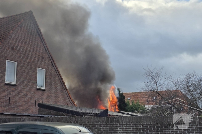 Vlammen, explosies en zwarte rook bij brand achter woning