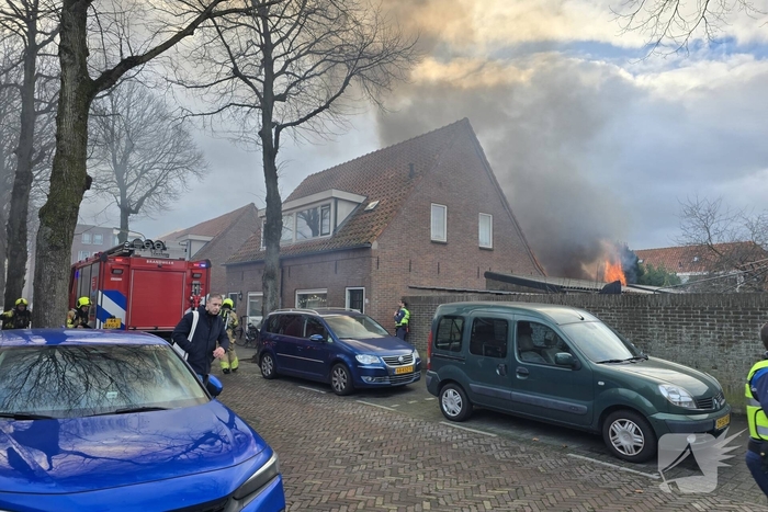 Vlammen, explosies en zwarte rook bij brand achter woning
