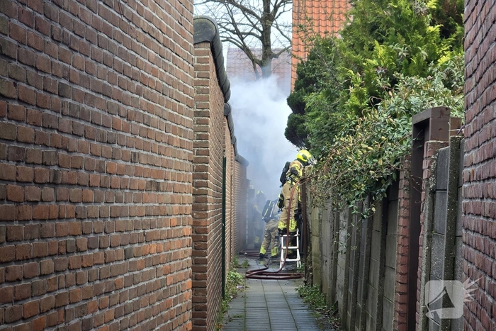 Vlammen, explosies en zwarte rook bij brand achter woning