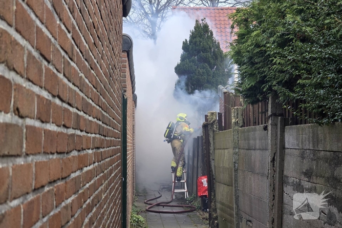 Vlammen, explosies en zwarte rook bij brand achter woning