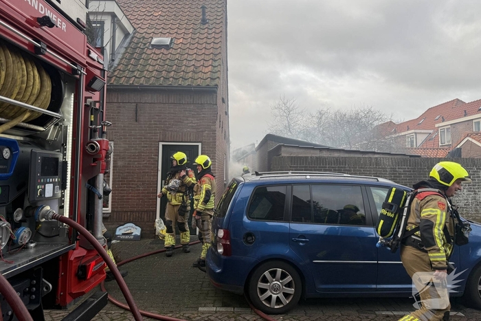 Vlammen, explosies en zwarte rook bij brand achter woning