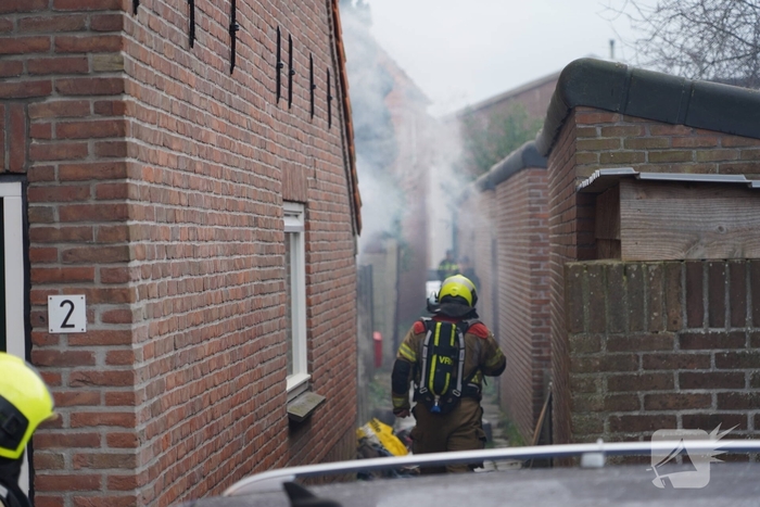Vlammen, explosies en zwarte rook bij brand achter woning