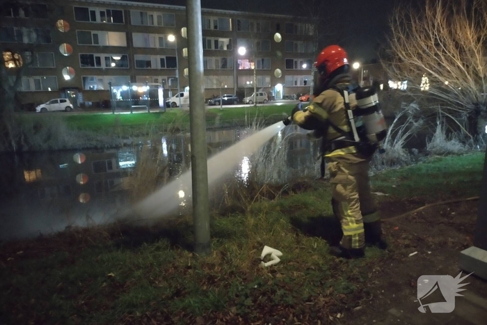 Brandweer blust brand langs sloot