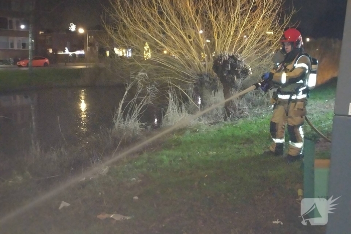 Brandweer blust brand langs sloot