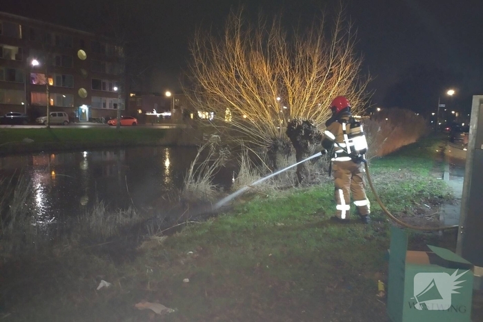 Brandweer blust brand langs sloot