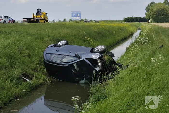 Auto belandt op zijkant in sloot naast snelweg