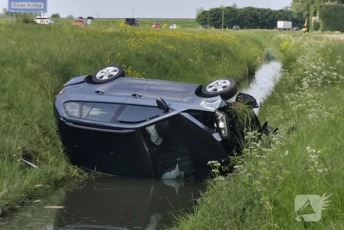 Auto belandt op zijkant in sloot naast snelweg