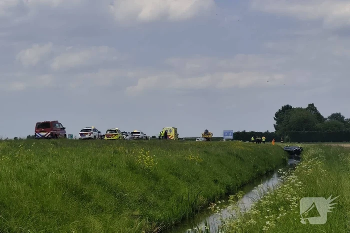 Auto belandt op zijkant in sloot naast snelweg