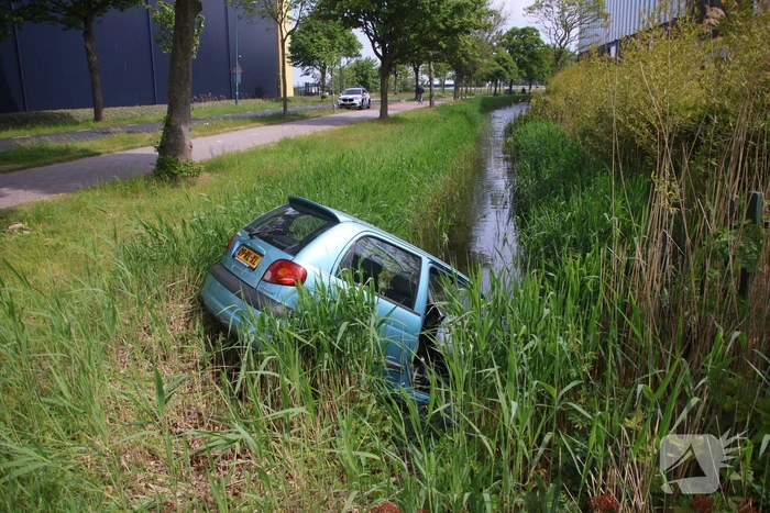 Omstanders halen inzittenden uit te water geraakt voertuig