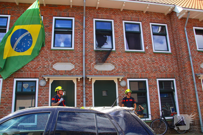 Verrotte boom valt op auto en tegen woning
