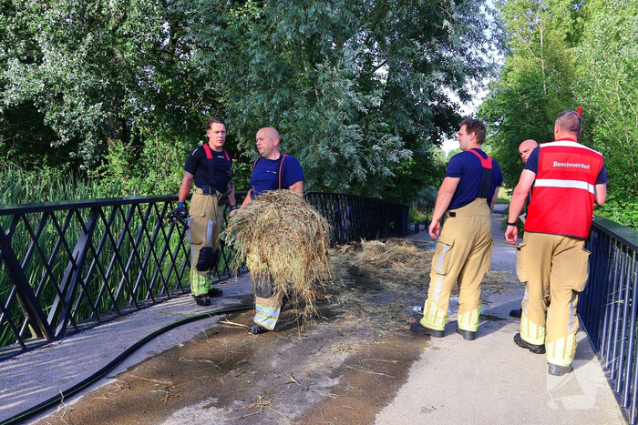 Brandweer blust brandende hooibaal