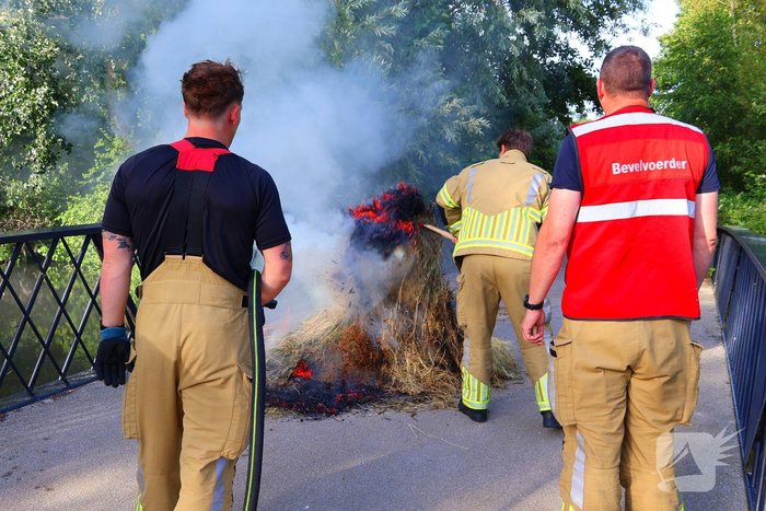 Brandweer blust brandende hooibaal