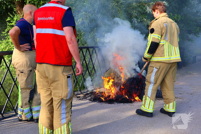 Brandweer blust brandende hooibaal