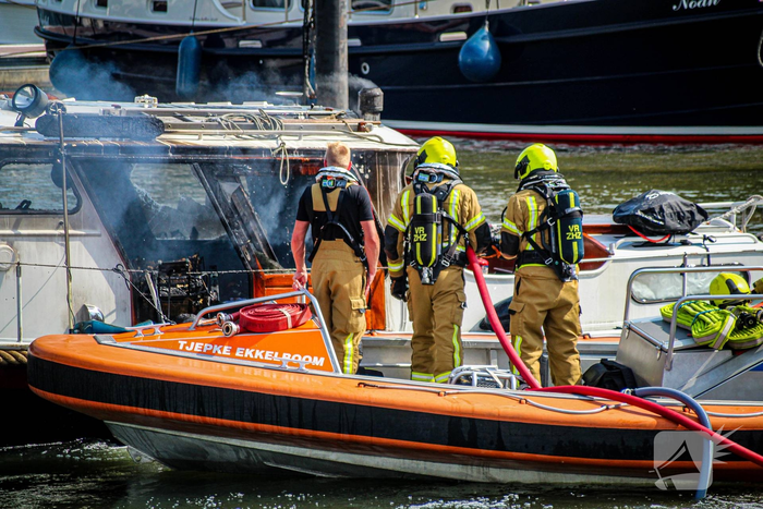 Bemanning zeeschip start blussing van brandend jacht