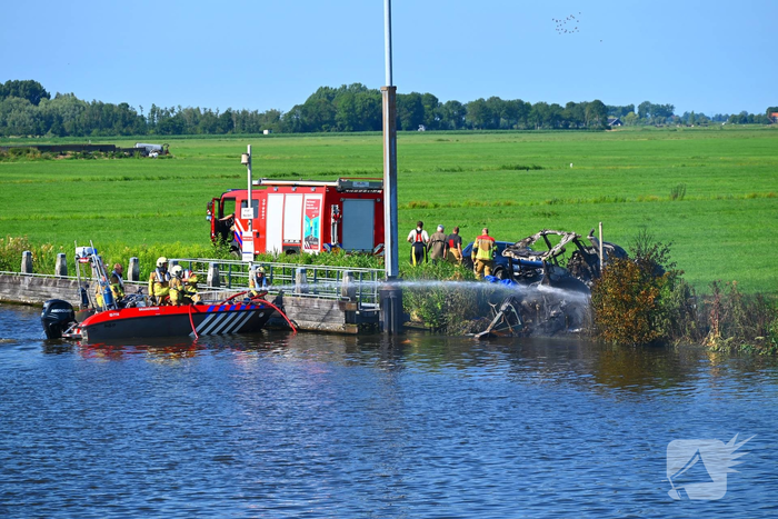 Tractor brandt uit langs waterkant, blusboot ingezet