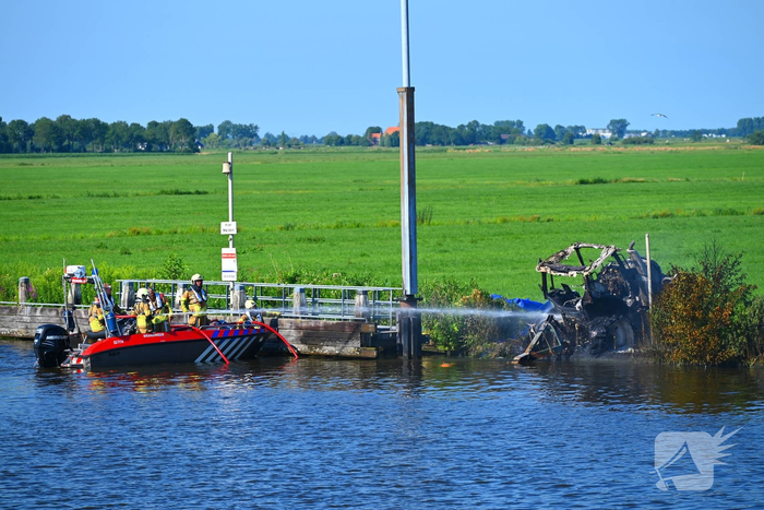 Tractor brandt uit langs waterkant, blusboot ingezet