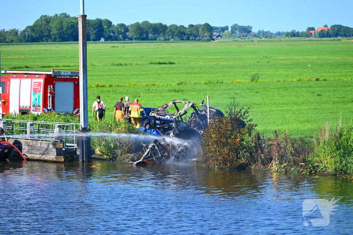 Tractor brandt uit langs waterkant, blusboot ingezet