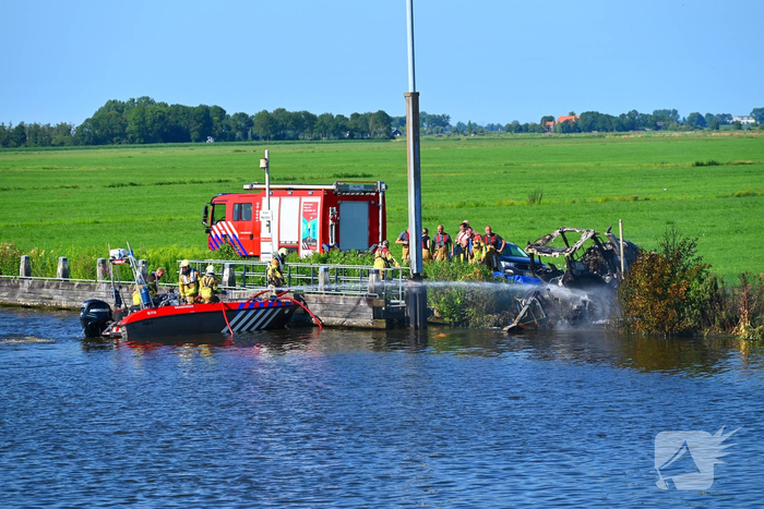 Tractor brandt uit langs waterkant, blusboot ingezet
