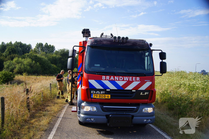 Brandweer blust brand in berm van dijk