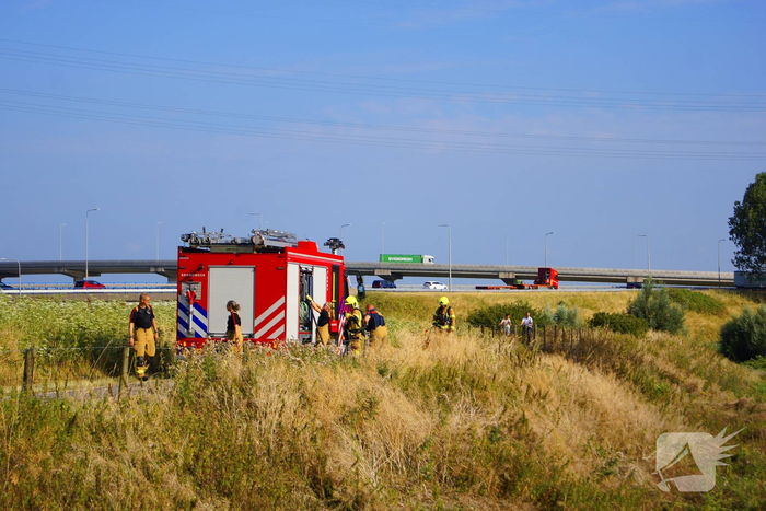 Brandweer blust brand in berm van dijk