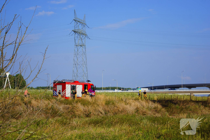 Brandweer blust brand in berm van dijk