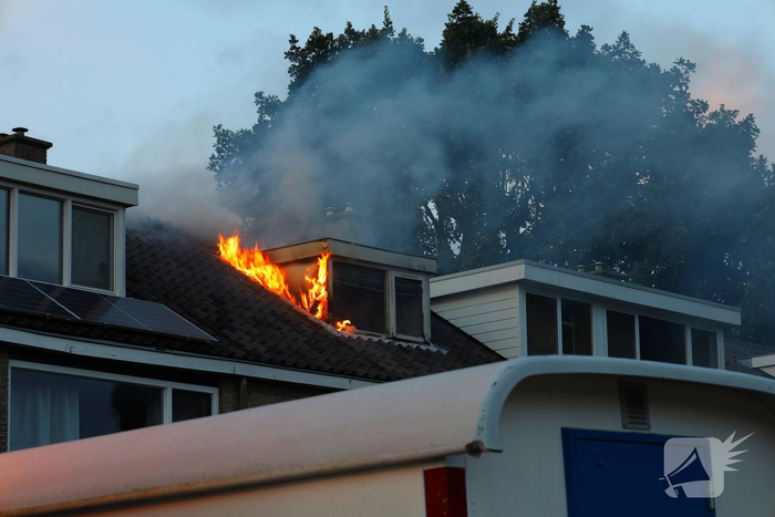 Dakkapel in vlammen, brandweer schaalt op