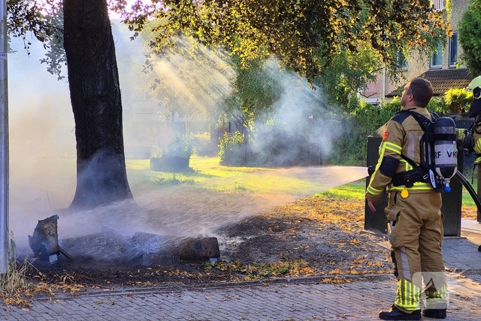 Brandweer blust brandend object tegen boom
