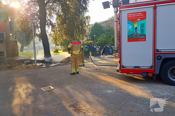 Brandweer blust brandend object tegen boom