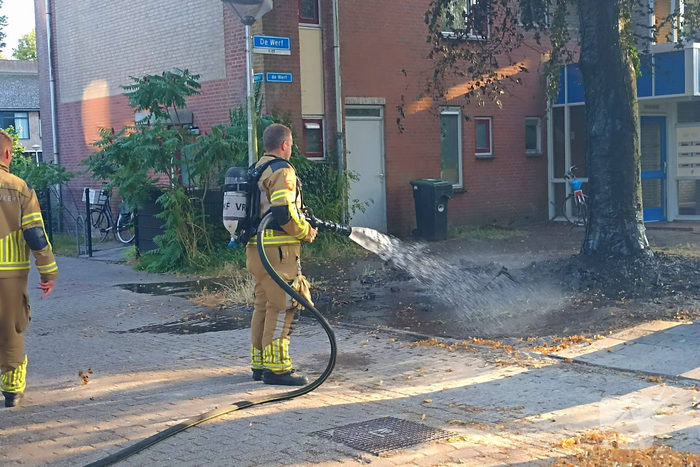 Brandweer blust brandend object tegen boom