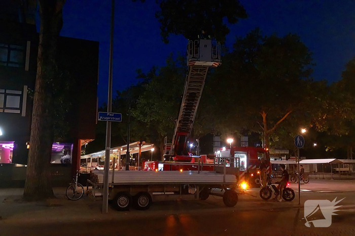 Brandweer haalt parasol uit boom met autoladder